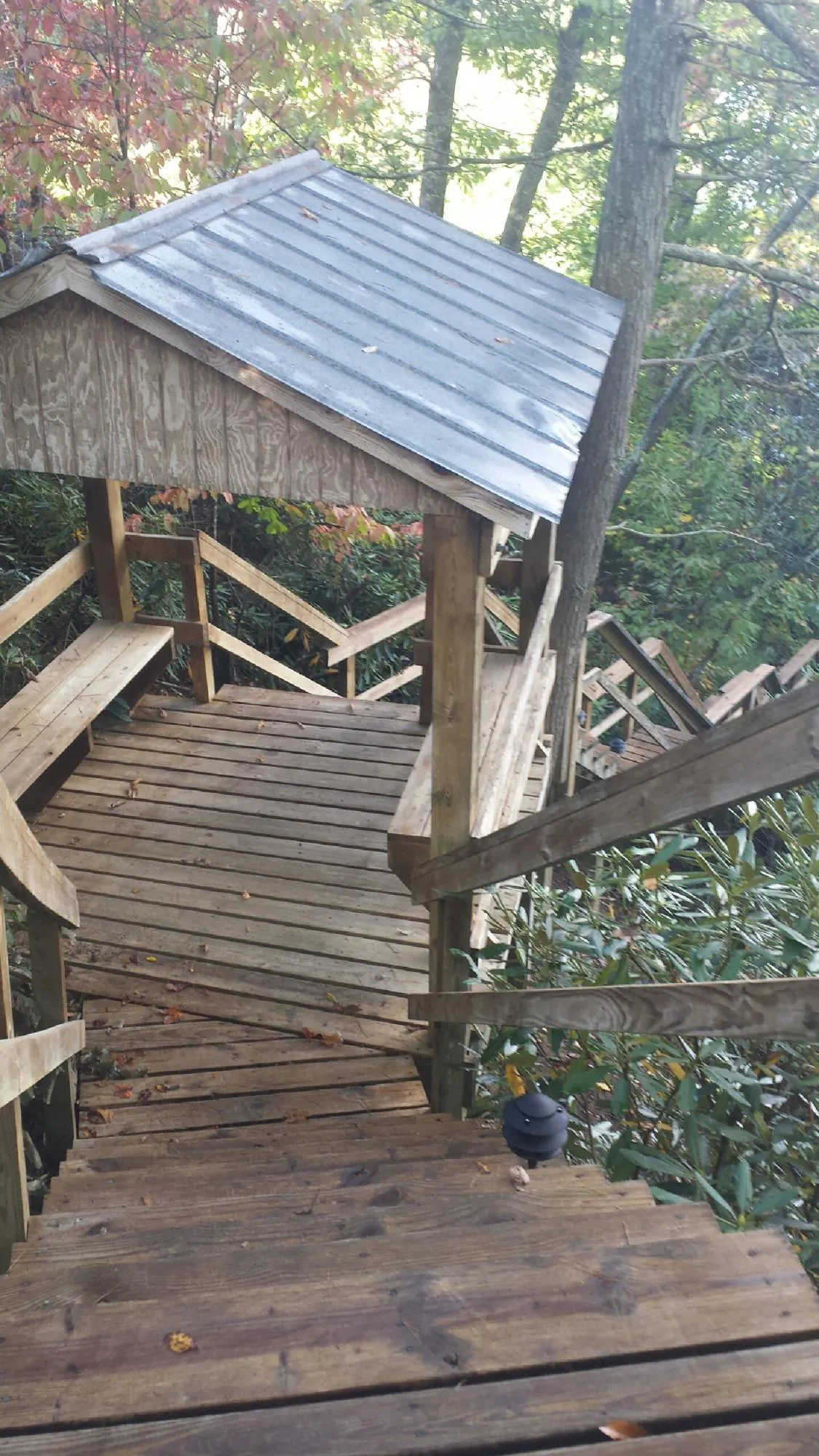Metal roofed shelter over wooden steps on a wooded walkway — Skylight Repair & Installation work by our crew in Oneida